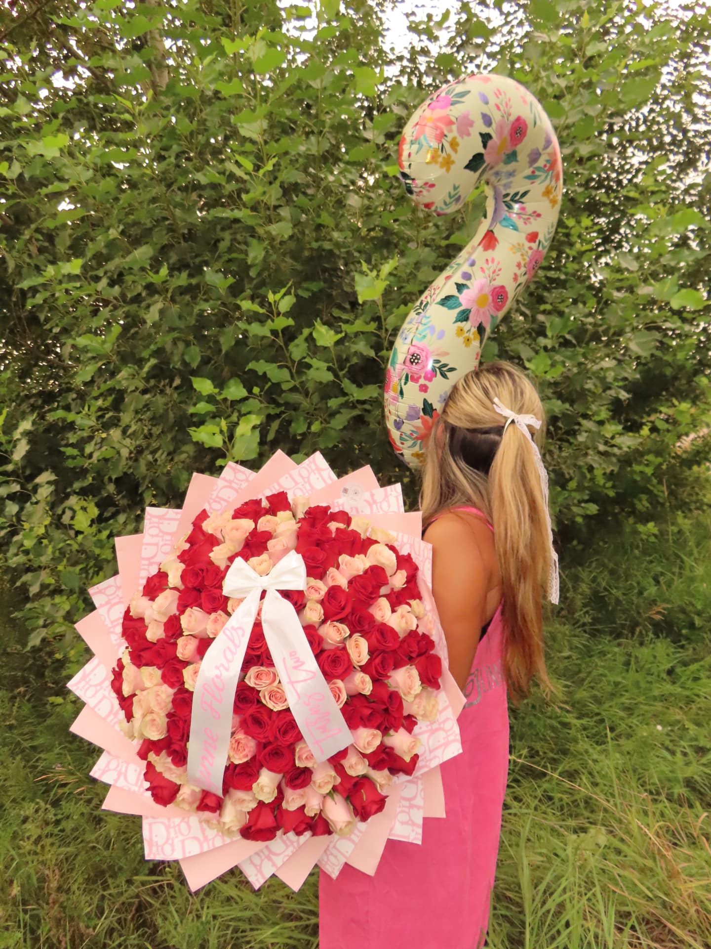 Large red and cream rose bouquet with a floral balloon outdoors